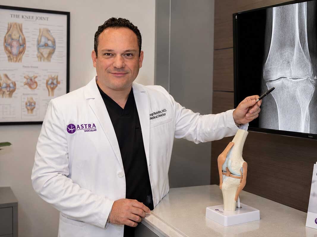 Dr. George Bolotin reviewing a knee X-ray during a follow-up visit after genicular artery embolization recovery at Astra Knee Pain Center.